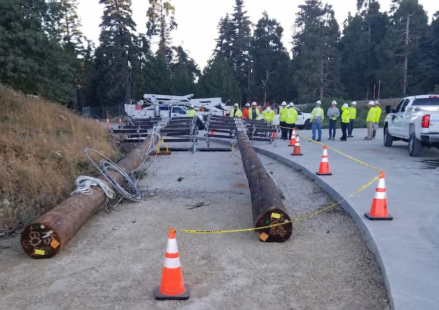 Utility construction crew, equipment and staged power poles during infrastructure field operations